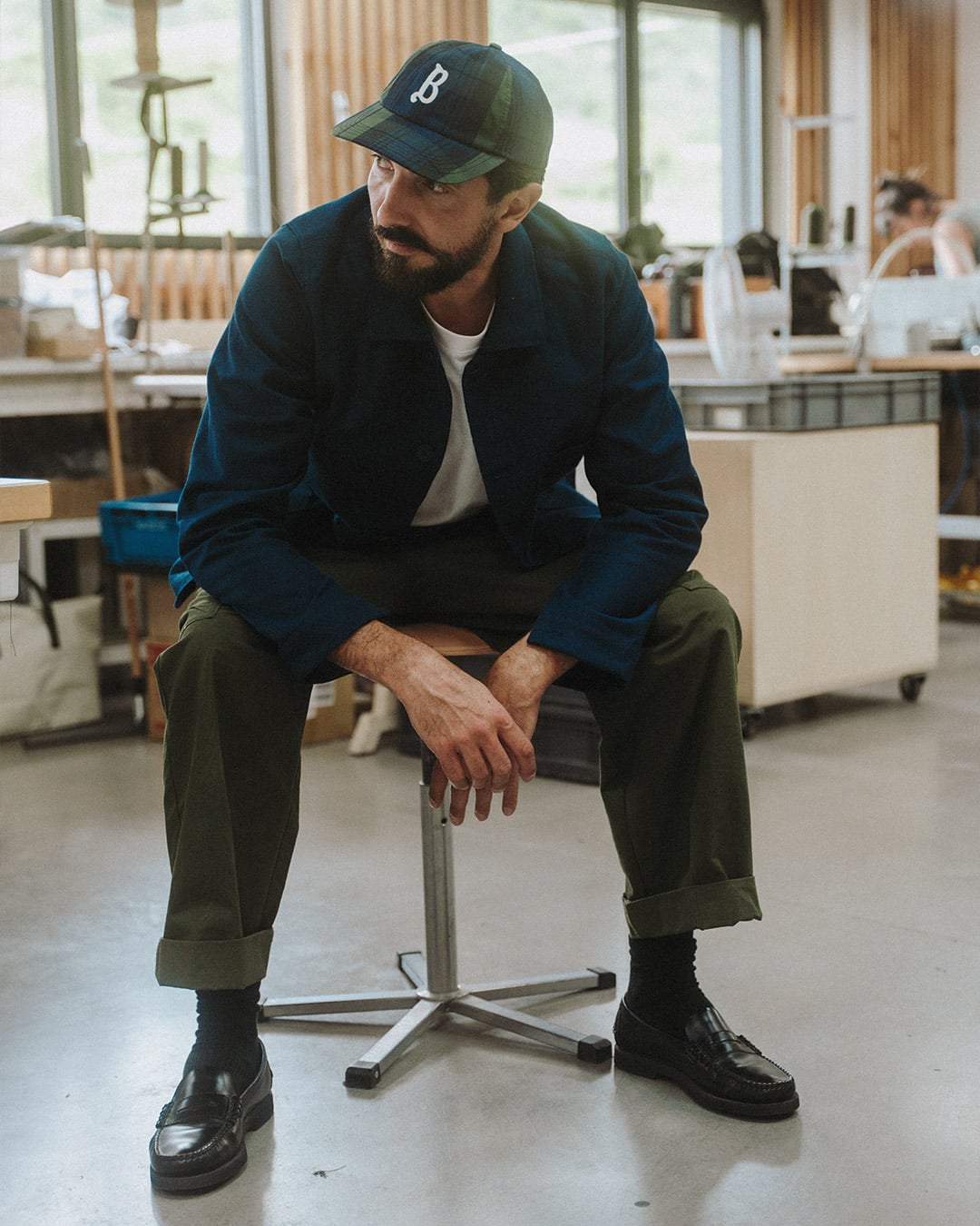 Un homme est assis dans l'atelier de Bleu de Chauffe et porte la casquette "Gaspard"