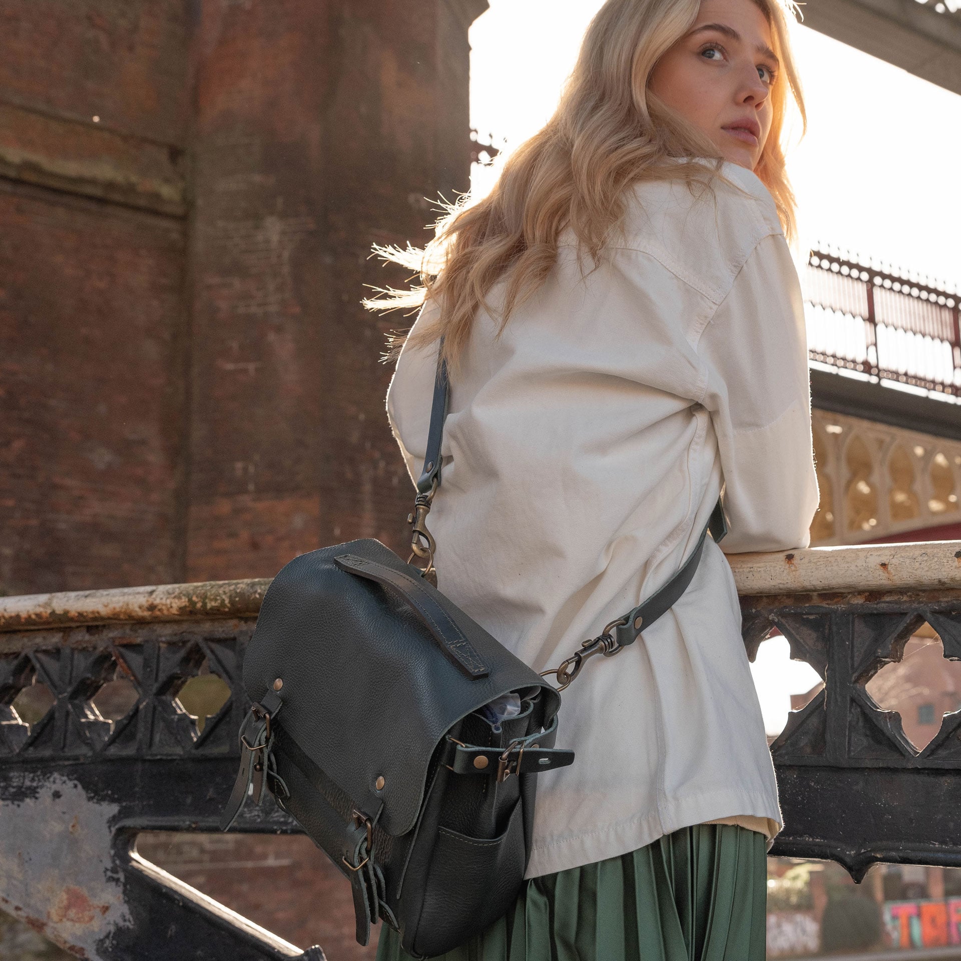 Une femme regadre au dessus de osn &eacute;paule en ville, elle porte le sac en cuir "Eclair"