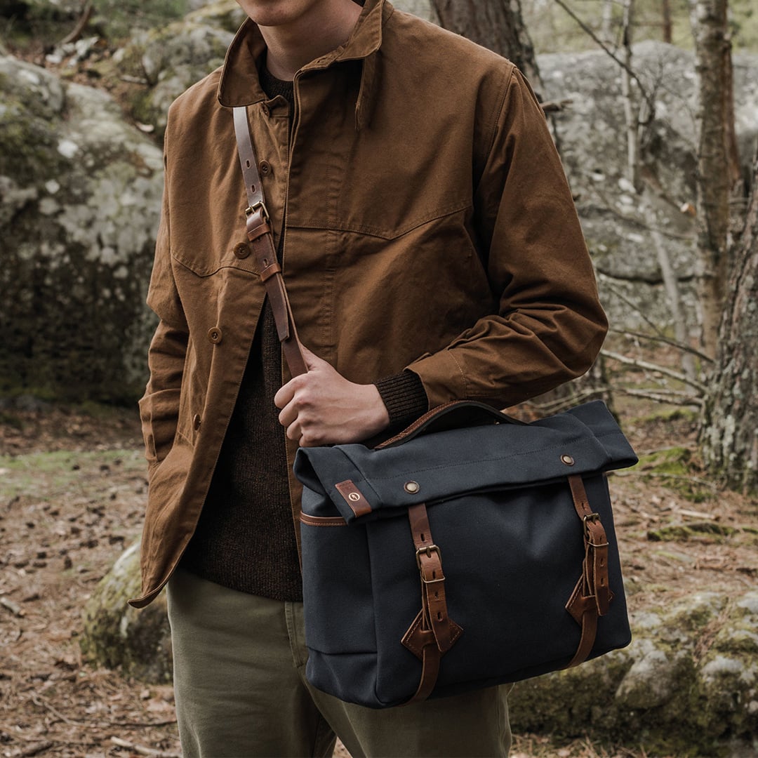 Un homme porte en bandouili&egrave;re le sac musette Gaston coloris Bleu Marin