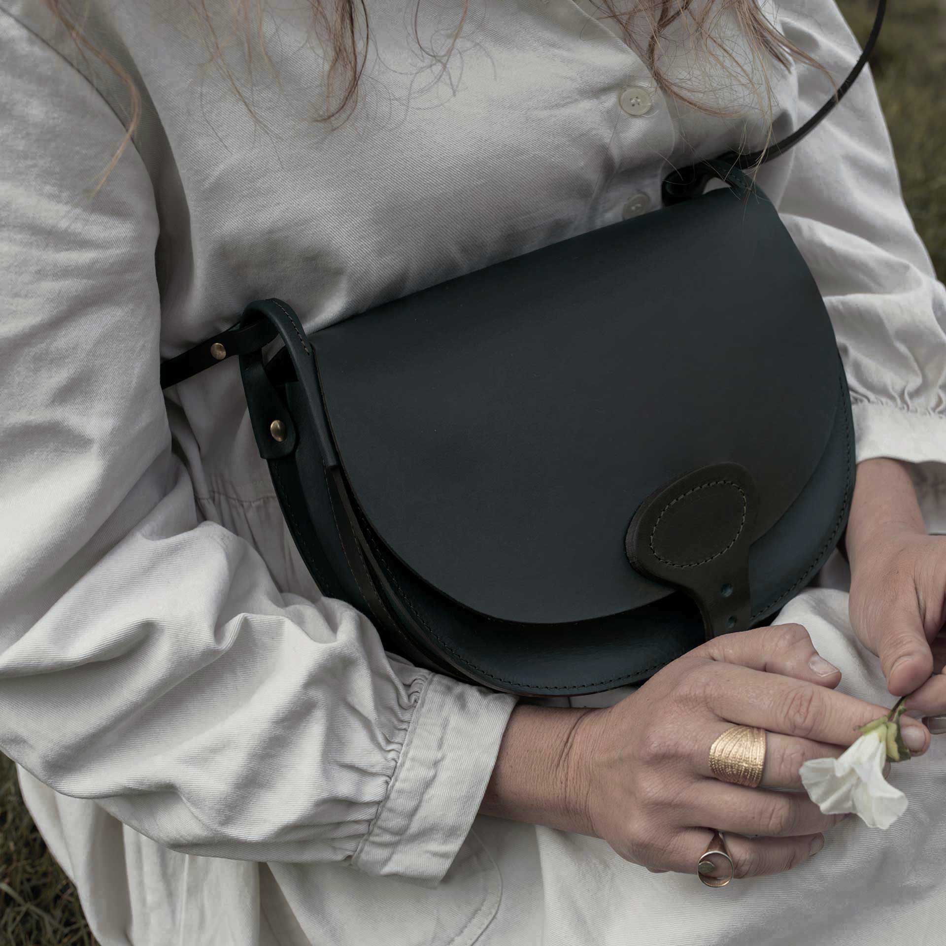 Une femme assise porte un sac besace