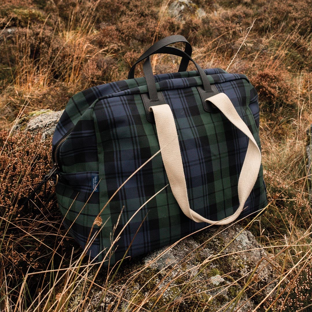 Vue 3/4 du sac de voyage en toile Missak, au mileu des hautes herbes
