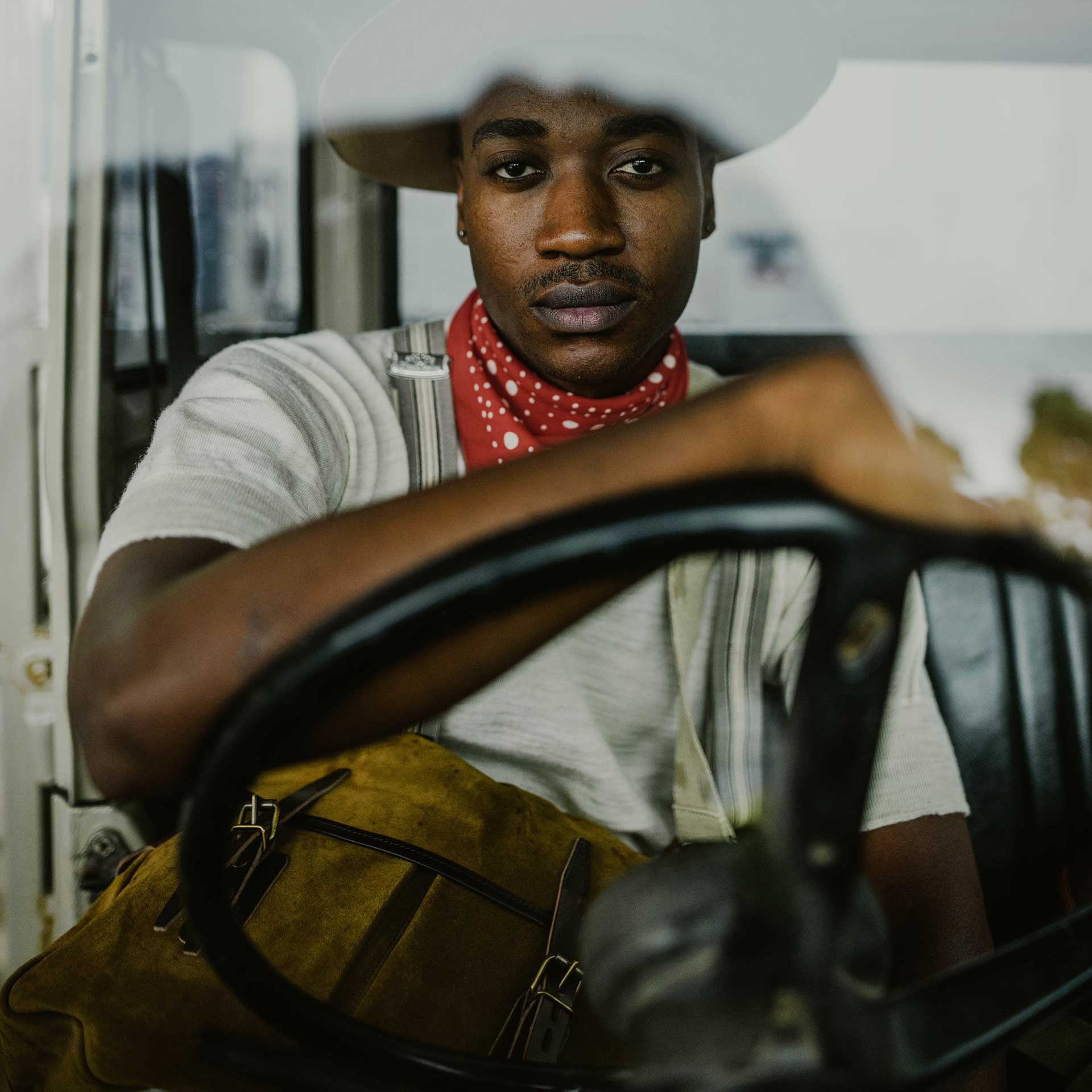 Front view photo of a man in a car carrying his high-end suede leather bag