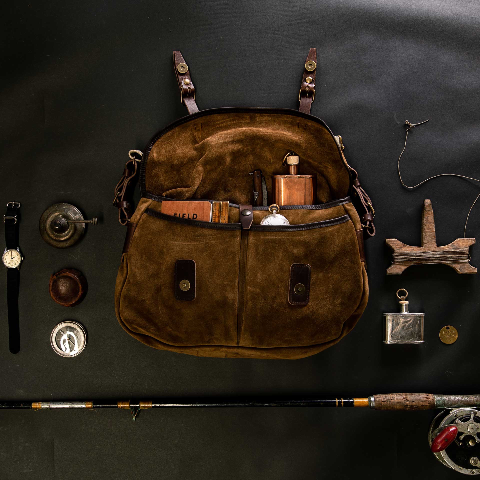 suede messenger bag and various fishing accessories, top view