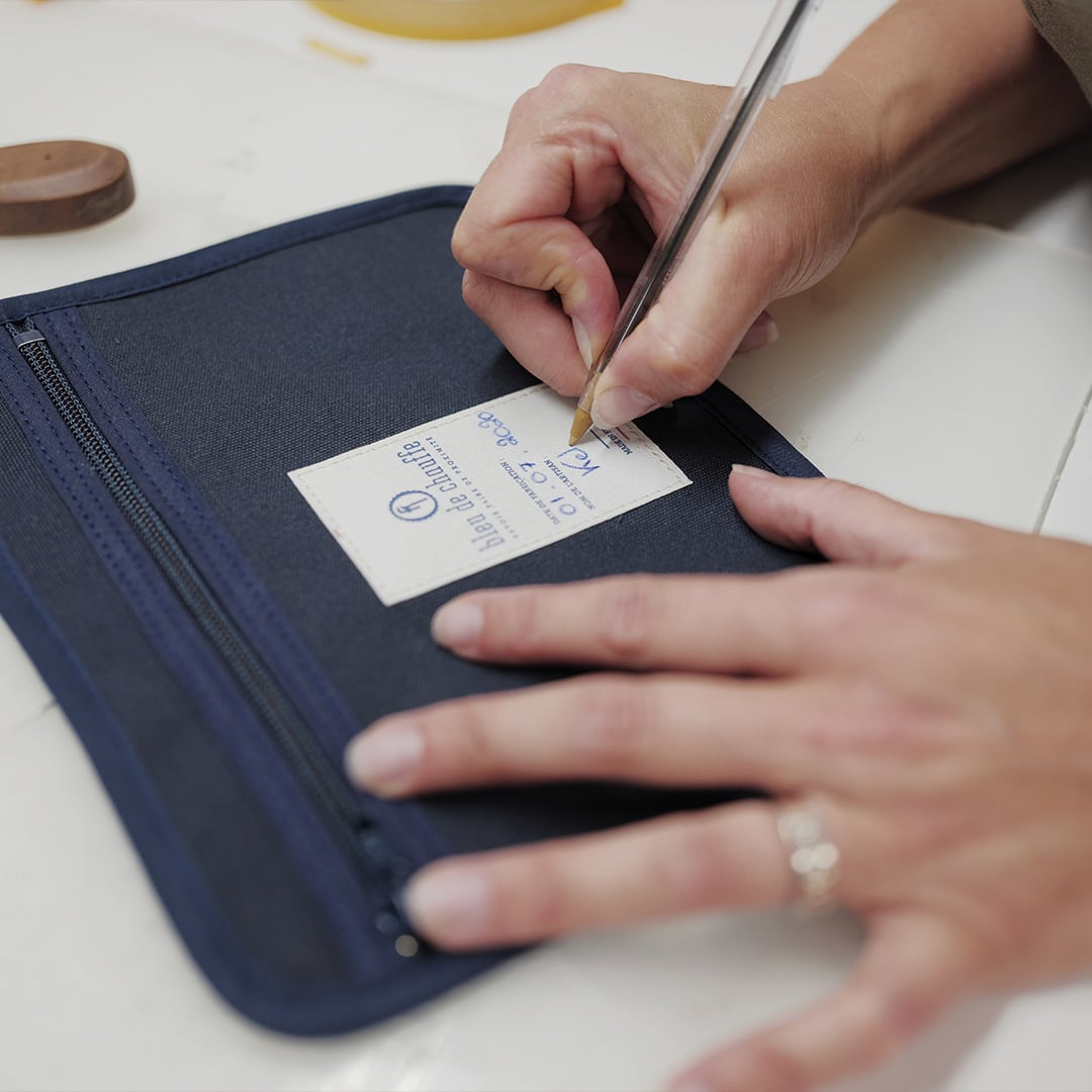 Un artesano firma el interior de un bolso.