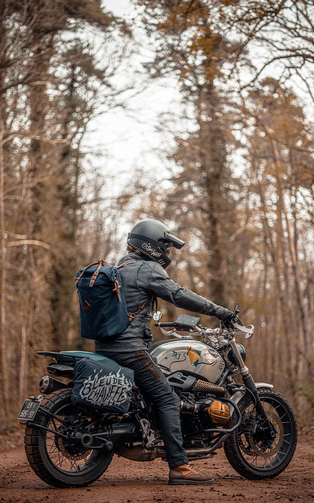 Un homme sur sa moto avec un sac a dos en toile et un sac moto accroch&eacute; &agrave; l'arriere