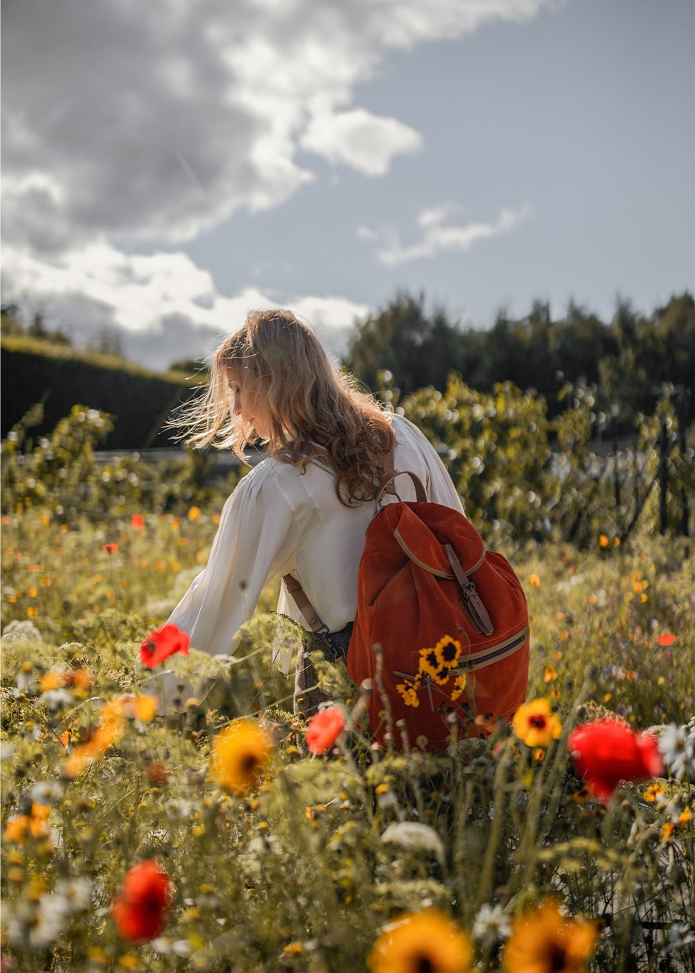 Une femme entour&eacute;e de fleur porte un sac a dos en cuir