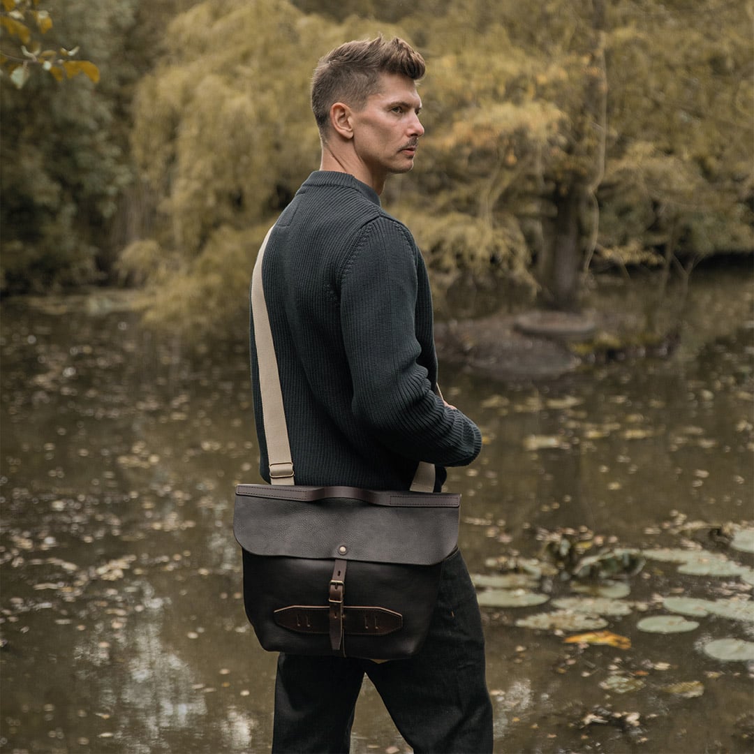 Un homme porte &agrave; l'&eacute;paule sa besace elazar devant un lac