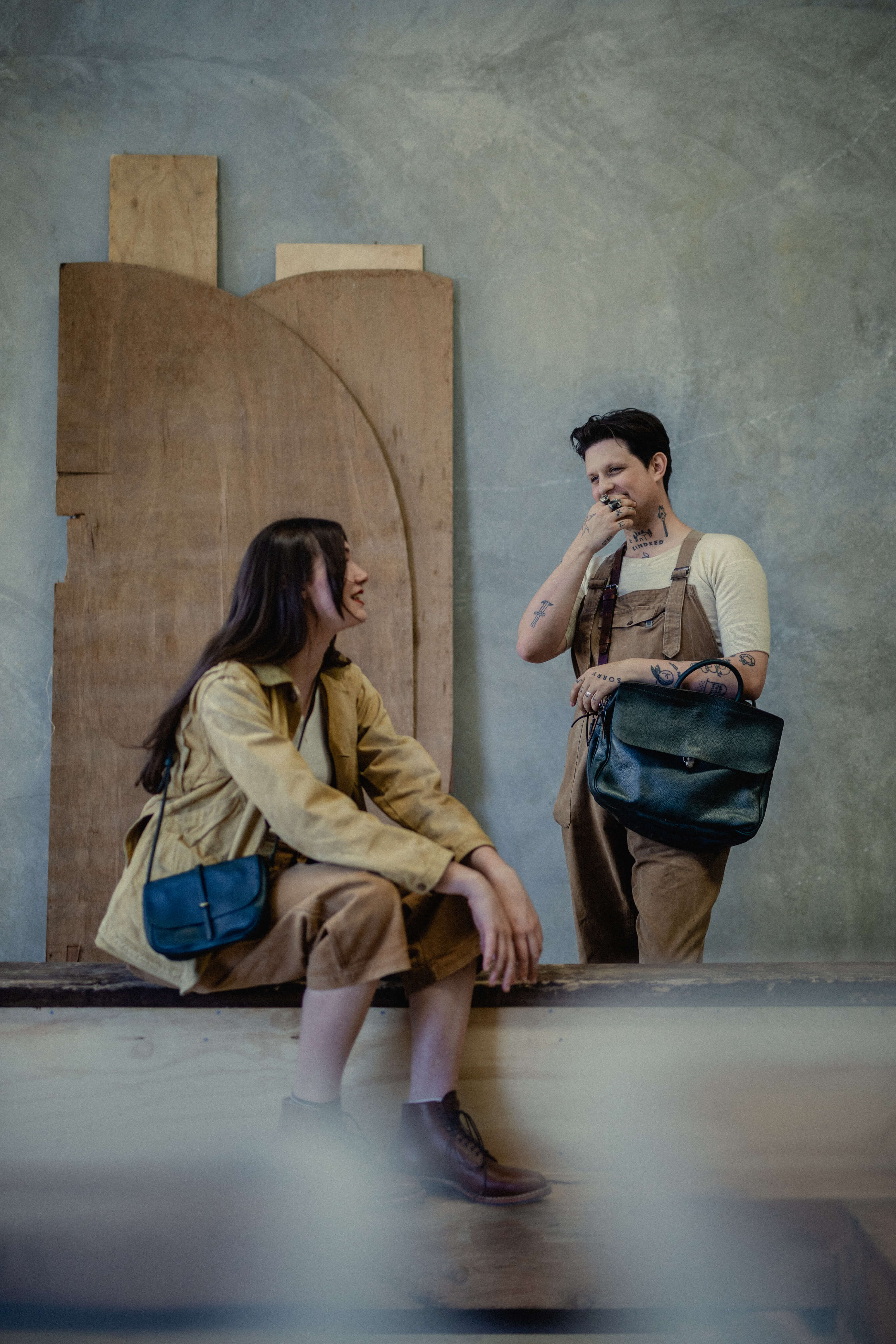 on the left a woman carries a handmade handbag and on the right a man carries a leather computer bag
