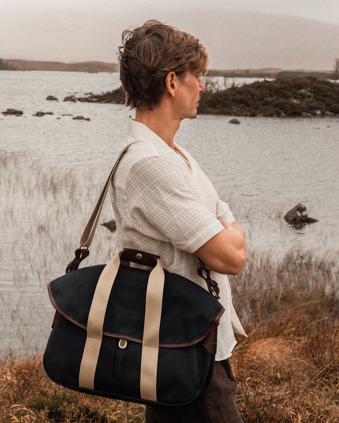 Un hombre en plena naturaleza lleva al hombro la bolsa «musette business - navy» bm.