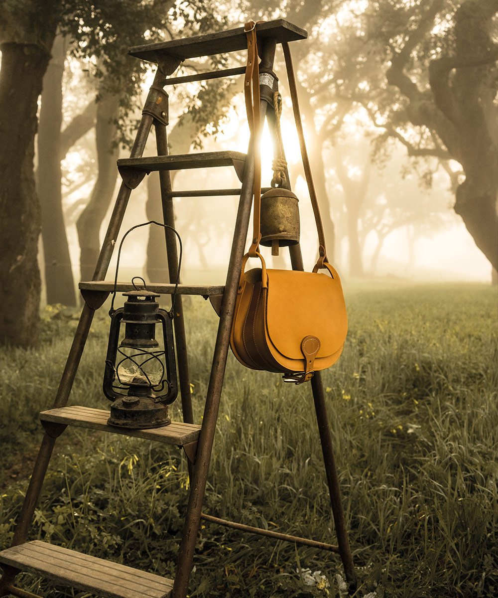 une gibeciere en cuir est pendu &agrave; un tabouret en bois
