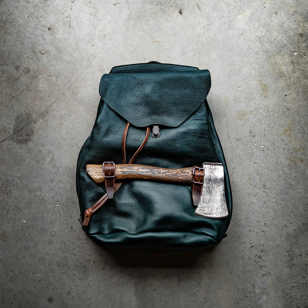 Une hache est accroch&eacute; a un sac a dos en cuir 