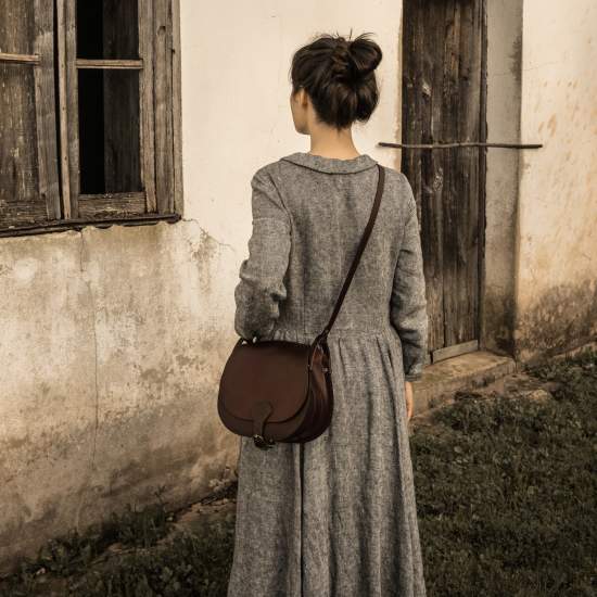 Une femme de dos porte un sac a main en cuir 